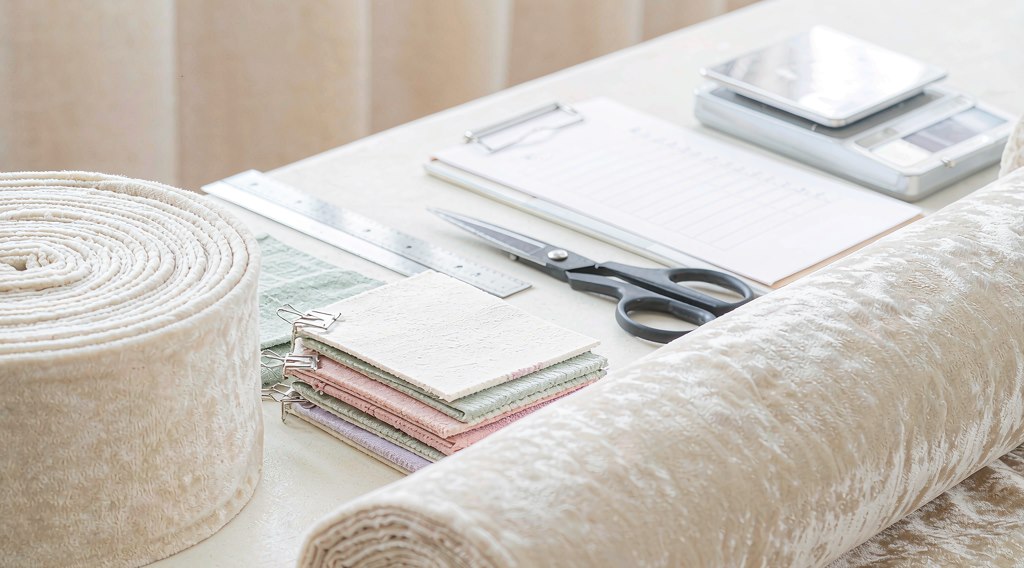 Plush fabric rolls, fabric swatch cards and a quality checklist on an inspection table
