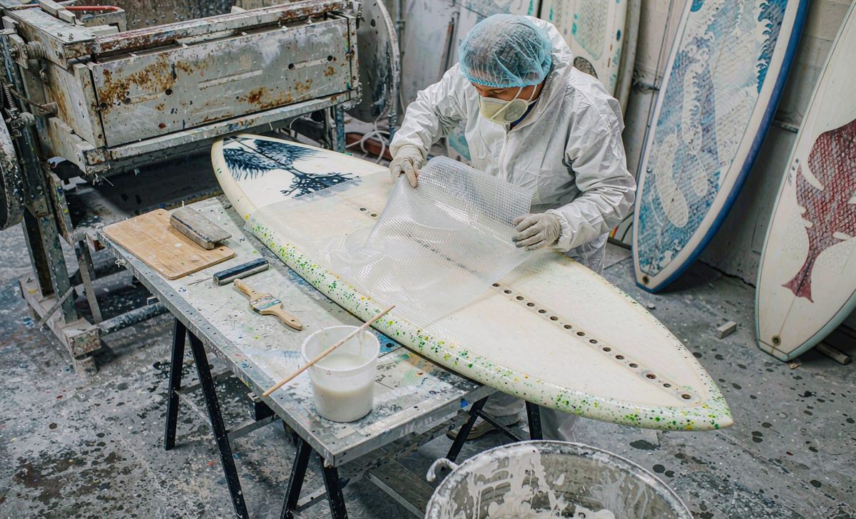 Laying glass fibre cloth over a paddleboard blank in the workshop