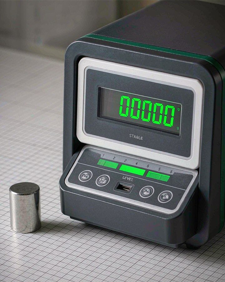 Bench balance with a stable green readout, a level indicator and a reference weight beside it
