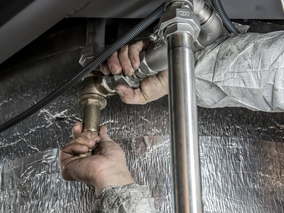 Installer tightening a connection on a pipe run